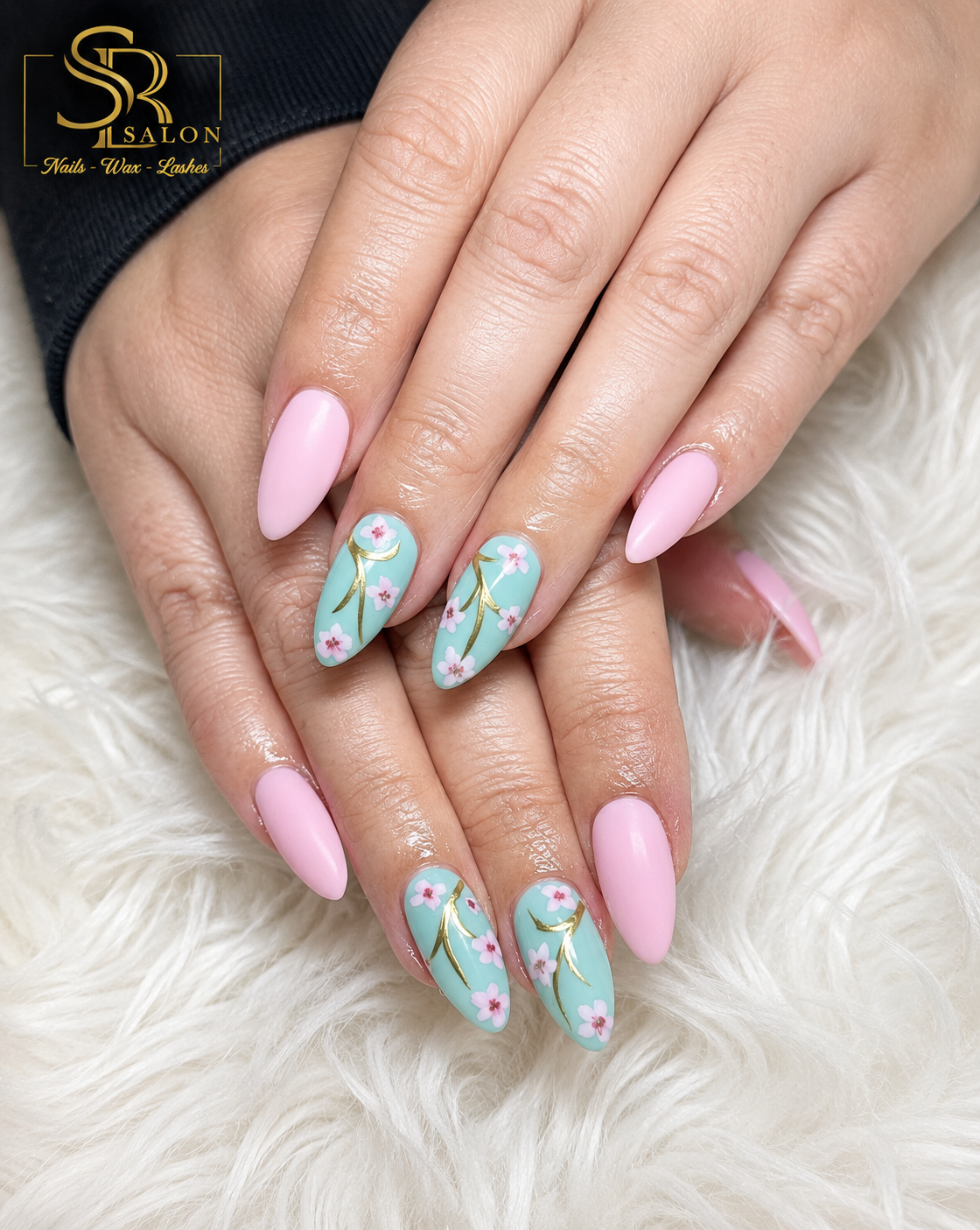 Mint green almond nails with pink cherry blossoms and gold accent branches, paired with soft pink nails.