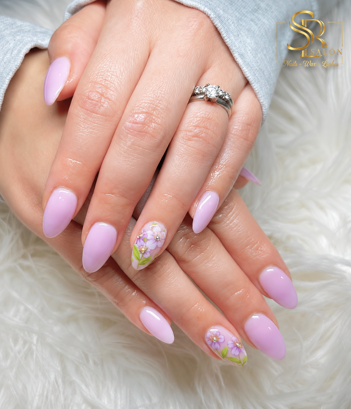 Soft lilac almond nails with delicate purple floral nail art and tiny gold accents.